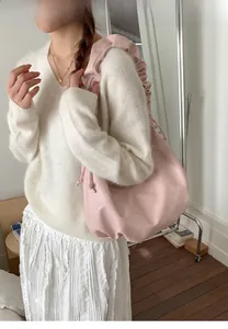 Detail of pink hobo bag featuring ruffled shoulder strap and drawstring closure