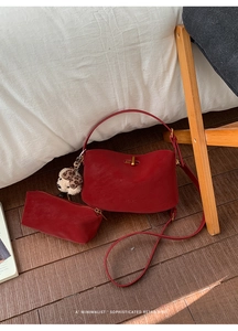Detail of red leather dumpling bag featuring Muheti logo and cute bear charm accessory