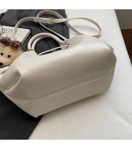 Détails de ce sac seau en cuir synthétique crème avec boucles dorées et porte-clés ours en peluche