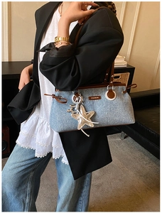Dettaglio della borsa bowling in denim con finiture in pelle marrone e ciondolo a stella