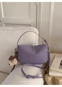 Detail view of a lavender dumpling bag with a metal lock and a cute plush dog charm