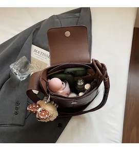 Interior view of brown lychee leather bucket bag with daily items and plush bear charm