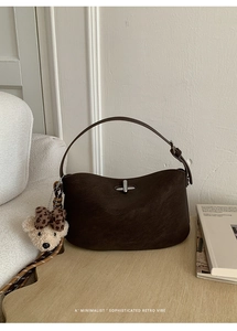 Detail of dark brown retro crescent bag with silver twist lock and plush bear charm