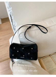 Détail du sac Boston en daim noir avec rivets étoiles argentés et logo de la marque