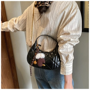 Close-up of quilted black moon bag with gold chain strap and plush glove charm