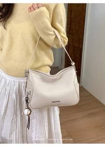 Detail of cream leather shoulder bag with PANTOR metal logo and baseball pendant