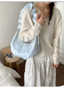Detailed view of the light blue crescent bag with elegant ruffled pleats on the shoulder strap