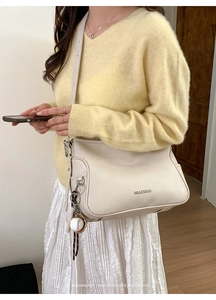 Minimalist beige leather shoulder bag with Fantoor logo shown on model in cozy home setting