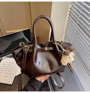 Détail du sac en cuir ciré marron foncé avec ferrures dorées et breloque chiot en peluche