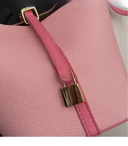 Close-up of pink litchi grain leather bucket bag featuring gold metal lock and stitching