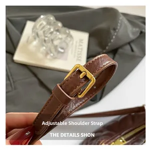 Detail of adjustable leather shoulder strap with vintage gold buckle on a brown handbag