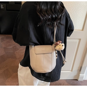 Detail of cream bucket bag featuring a cute bear charm and beaded strap accessories