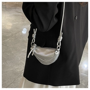 Mini sac selle argenté bandoulière avec détails de nœuds et fini métallisé sur modèle