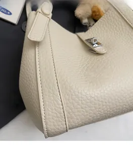 Gros plan d'un sac seau en cuir grainé blanc cassé avec fermoir pivotant en métal argenté