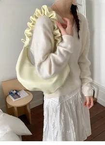 Detail of creamy yellow pleated shoulder strap and soft hobo bag material on model
