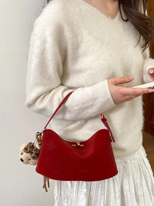 Elegant red leather handbag for women featuring a gold clasp and a cute plush bear charm