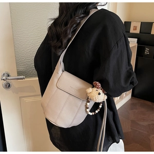 Detail of light grey lychee leather bucket bag with a cute plush bear charm accessory