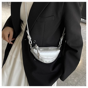 Détail du sac bandoulière argenté demi-lune avec bandoulière à nœud sur costume