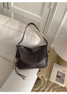 Detailed close-up of dark brown vintage shoulder bag with side pocket on a sofa