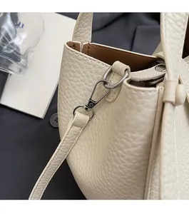 Détail de la boucle en métal argenté et du cuir grainé du sac seau crème