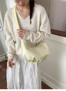 Detail of light beige pleated crescent bag with soft leather texture and wide strap