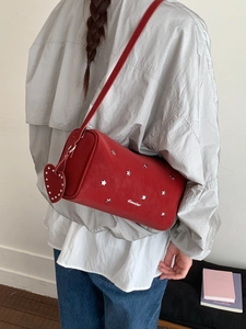 Sac cylindre en cuir rouge avec clous étoiles argentés et breloque cœur sur mannequin