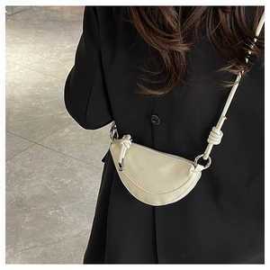 Détail du sac bandoulière demi-lune blanc cassé avec bandoulière nouée et boucles argent