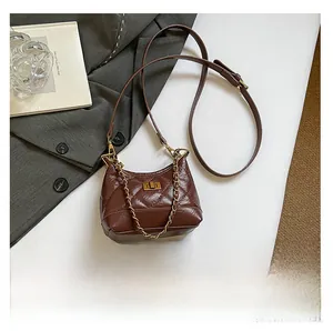 Detail view of mini quilted dark brown crossbody bag compared to a smartphone