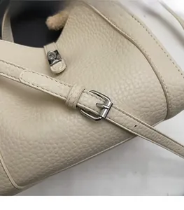 Détail de la bandoulière réglable et boucle argentée sur sac seau en cuir grainé crème