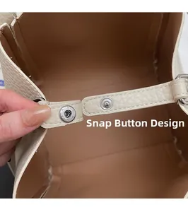 Gros plan détaillé d'un sac seau en cuir crème avec une fermeture à bouton-pression argenté