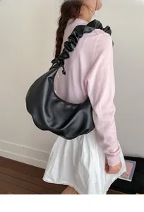 Detail of black pleated hobo bag with unique gathered shoulder strap and minimalist design