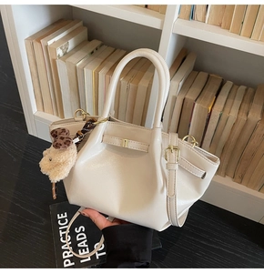 Détail du sac à main en cuir PU crème avec boucle dorée et breloque ours en peluche