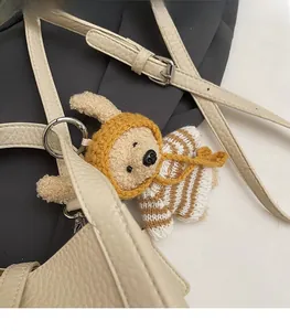 Gros plan d'un charme d'ours en peluche tricoté main sur un sac en cuir beige texturé