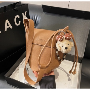 Detail of brown litchi pattern leather bag with plush bear charm and embossed logo