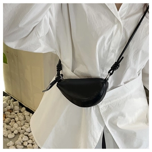 Détail du sac bandoulière demi-lune noir avec nœud décoratif sur la sangle d'épaule