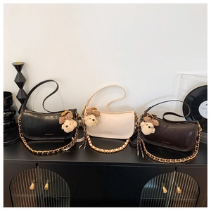 Three baguette bags in black, white and coffee on a vintage cabinet with plush bear charms