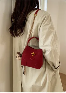 Détail du sac seau rouge mat avec bandoulière en chaîne dorée et pendentif ours mignon