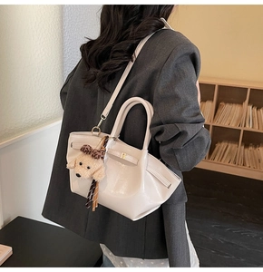 Détail du sac seau en cuir crème avec breloque chiot léopard et cordon de serrage latéral
