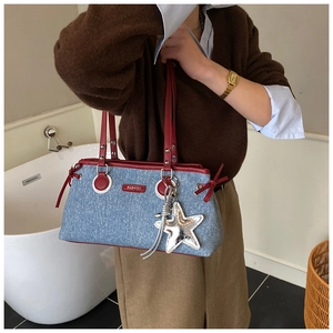Vue détaillée du sac bowling en denim avec poignées en cuir rouge et pendentif étoile