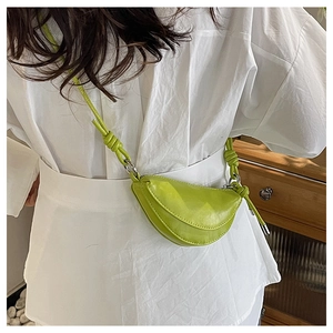 Sac bandoulière demi-lune vert vif avec détail de sangle nouée porté par un modèle
