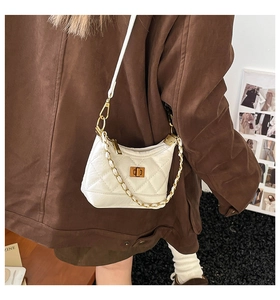 Close-up of white quilted leather texture with gold metal chain and twist-lock clasp