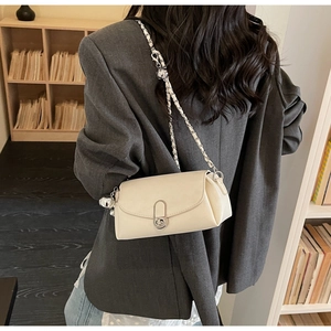 Elegante borsa a tracolla color crema con catena argento indossata su un blazer grigio