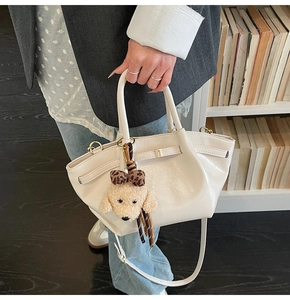 Détail du sac seau en cuir blanc crème avec charm chiot en peluche et boucle métallique