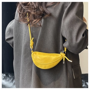 Détail du mini sac selle croissant jaune avec texture en cuir fin et bandoulières nouées