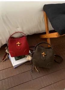 Détail de sacs seaux en daim bordeaux et olive avec verrous et charms léopard