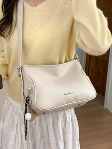 Minimalist beige leather shoulder bag with creative baseball pendant and silver logo