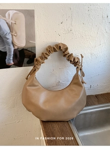 Detailed view of the pleated handle and bow knot on the khaki faux leather hobo bag