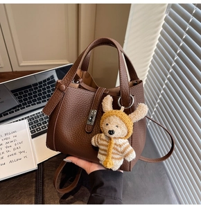 Détail de la texture cuir grainé marron foncé avec un charmant pendentif en forme d'ours en peluche