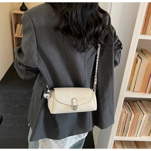 Vista dettagliata della borsa a tracolla beige con catena e ciondolo indossata