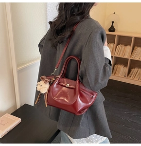 Détail du sac à main en similicuir bordeaux avec breloque ours et blazer gris